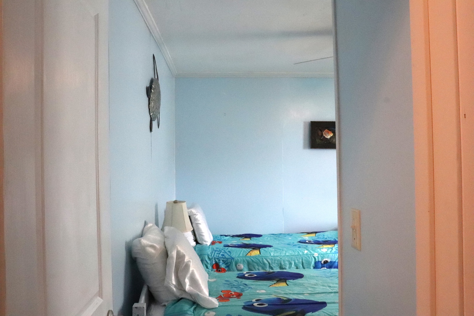 Step into your tranquil retreat with fresh white walls, cheerful marine-themed bedding, and thoughtful artwork that welcomes you home after each adventure.