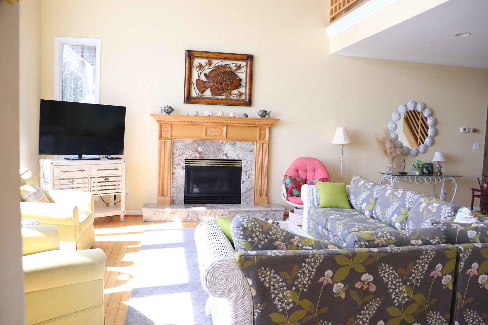 Relax in your cozy living room where natural light streams through windows, highlighting the warm fireplace and comfortable seating perfect for unwinding.