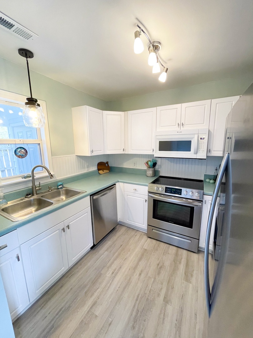 Your fully equipped kitchen features stainless steel appliances, ample cabinet space, and bright coastal-inspired colors for cooking memorable meals.