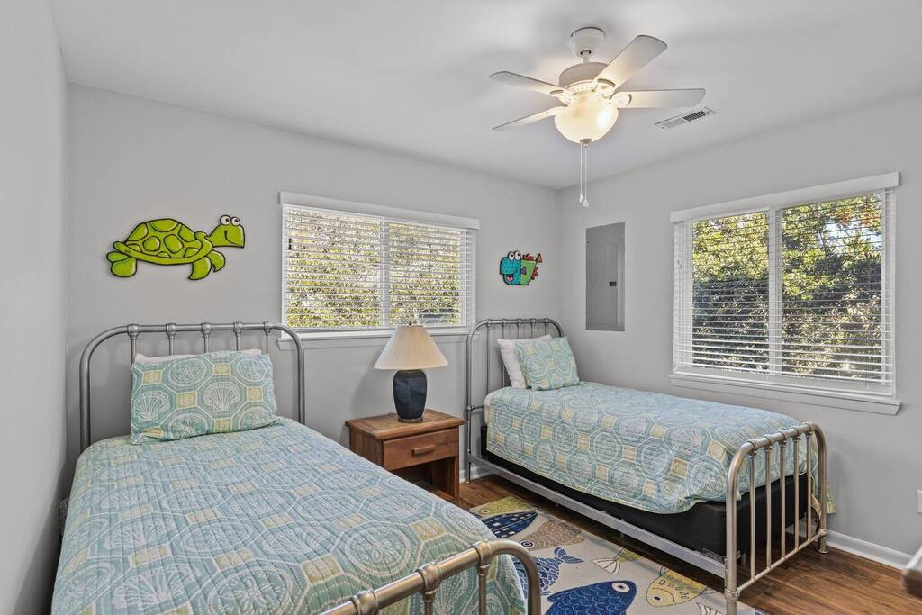 Your kids will love this cheerful twin bedroom with playful turtle decals and bright natural light streaming through multiple windows.