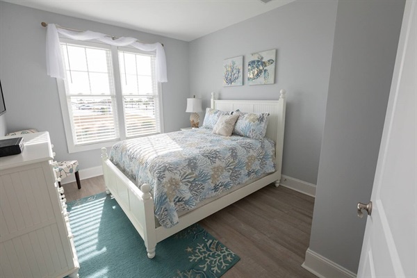 Your peaceful bedroom retreat features a comfortable bed with coastal-inspired linens, natural light streaming through windows, and soothing ocean-themed decor to help you unwind.