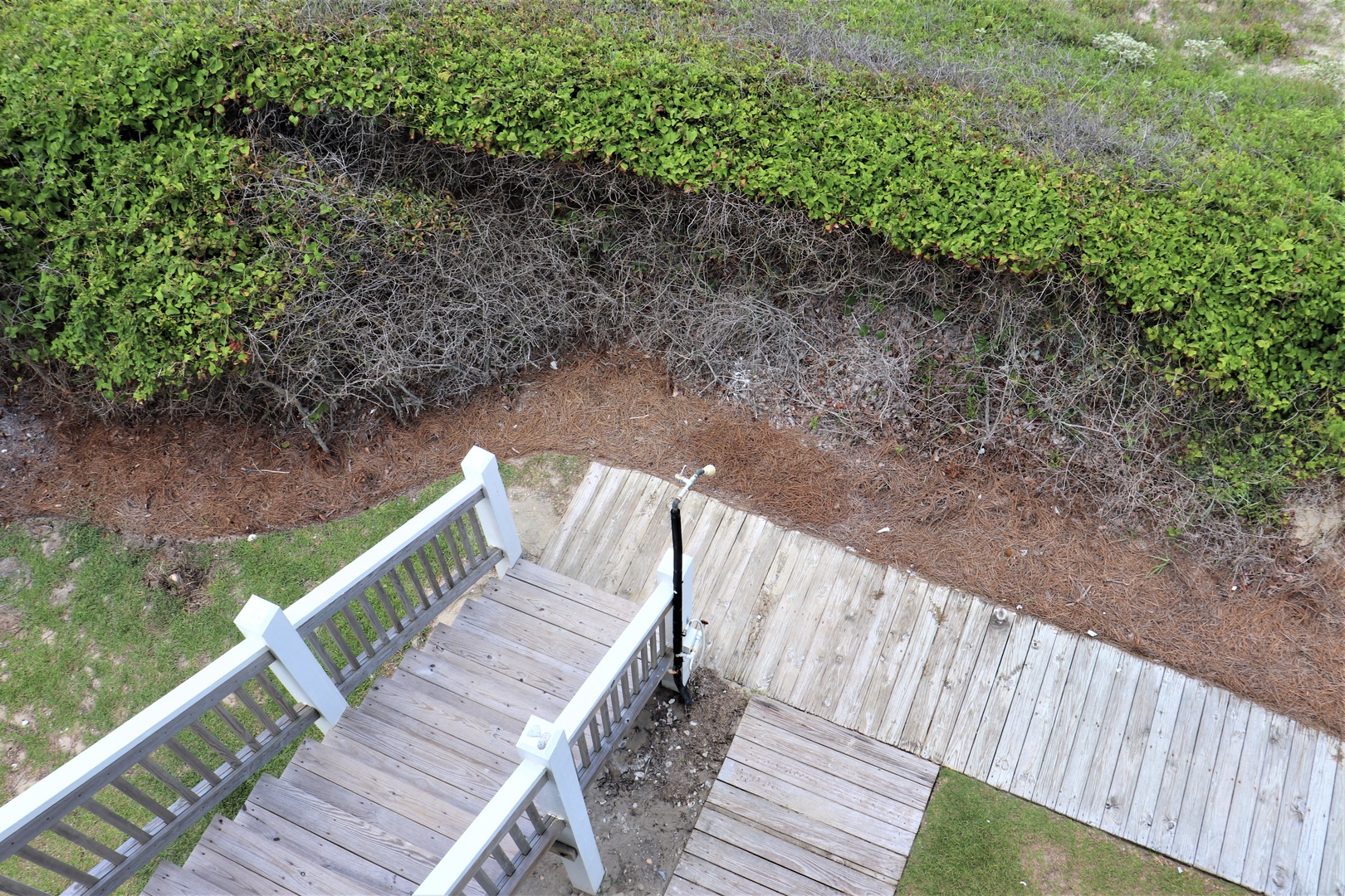Aerial view shows wooden boardwalk and stairs leading through natural dune vegetation to beach access.