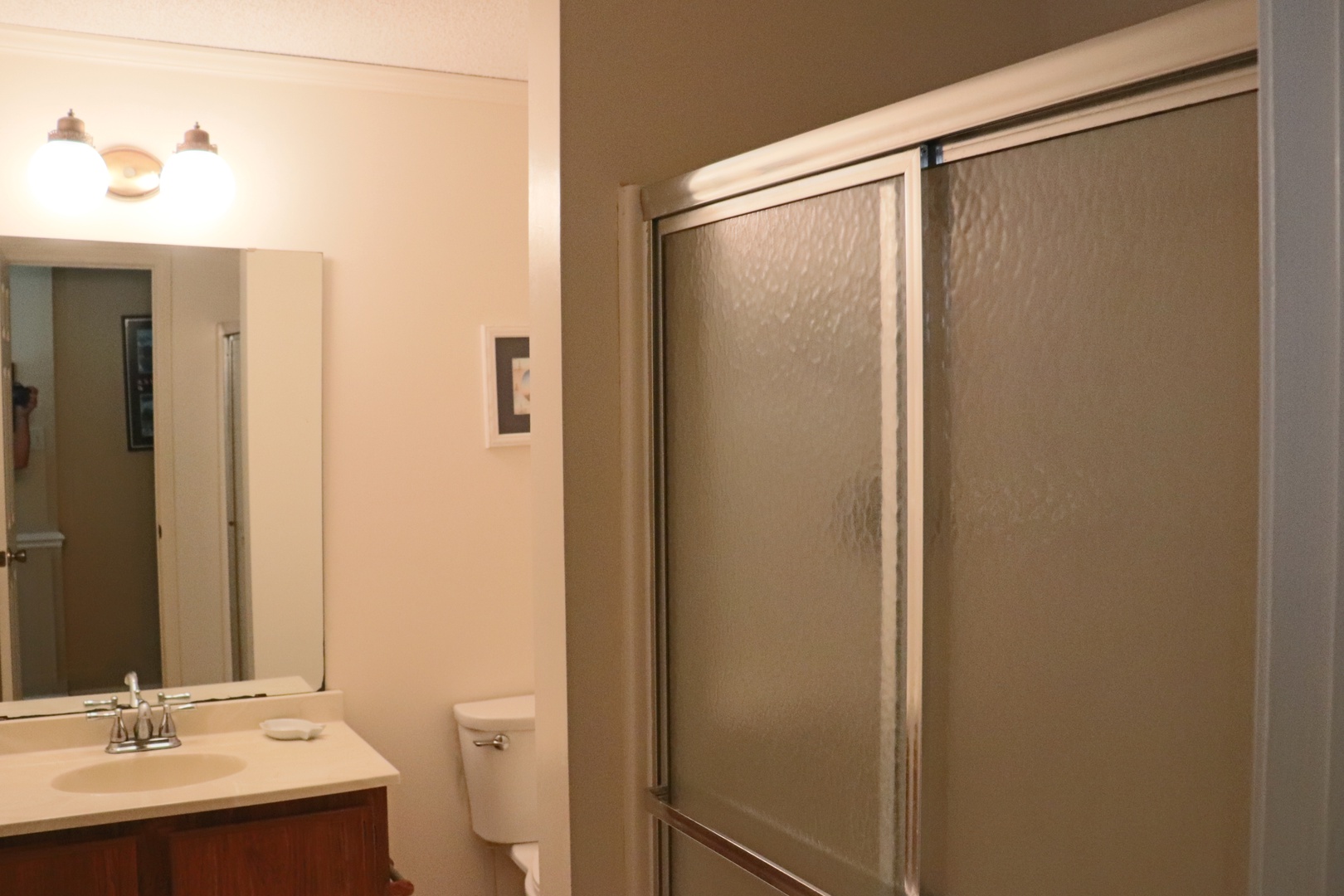 Your private bathroom features a sleek shower with frosted glass doors, vanity sink, and mirror - perfect for freshening up after your adventures.