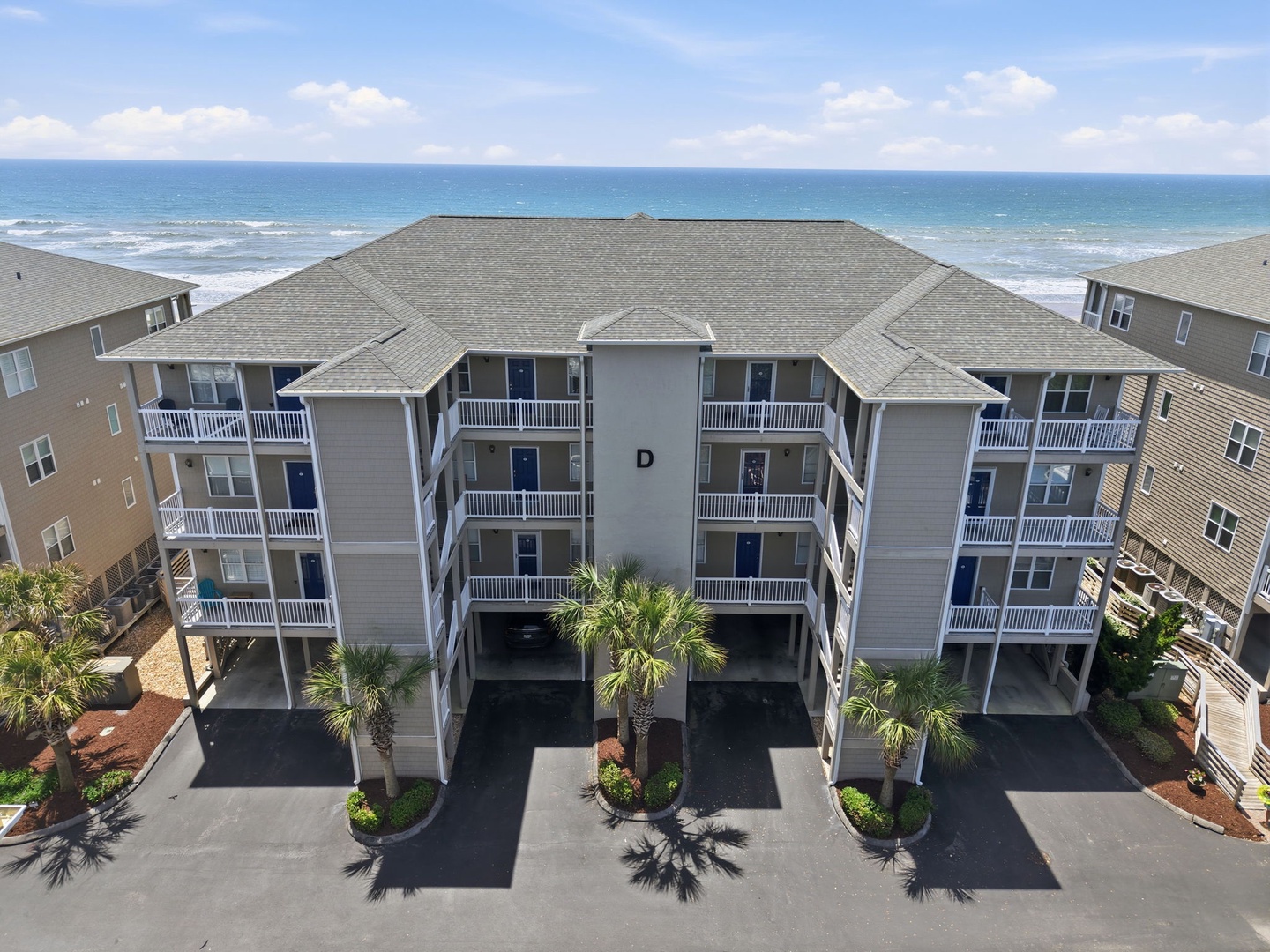 Beachfront property featuring multi-level condos with private balconies, situated steps from the Atlantic Ocean and surrounded by lush landscaping.