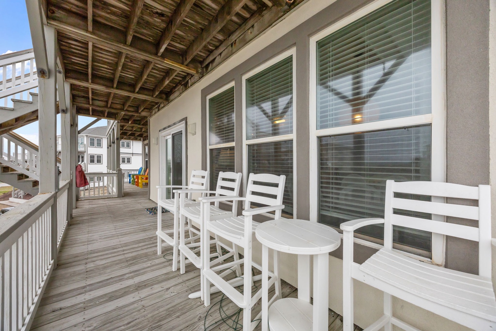 Your private covered porch offers coastal charm with white rocking chairs and a cozy table, perfect for morning coffee or sunset relaxation.