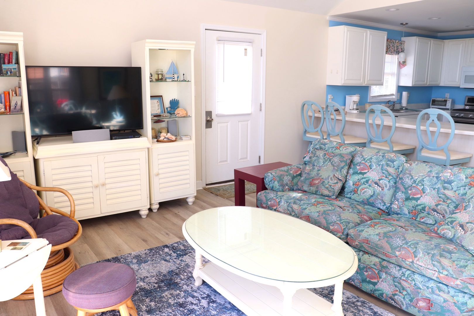 Relax in your bright, coastal-themed living space with comfortable seating, flat-screen TV, and open kitchen for easy meal prep.