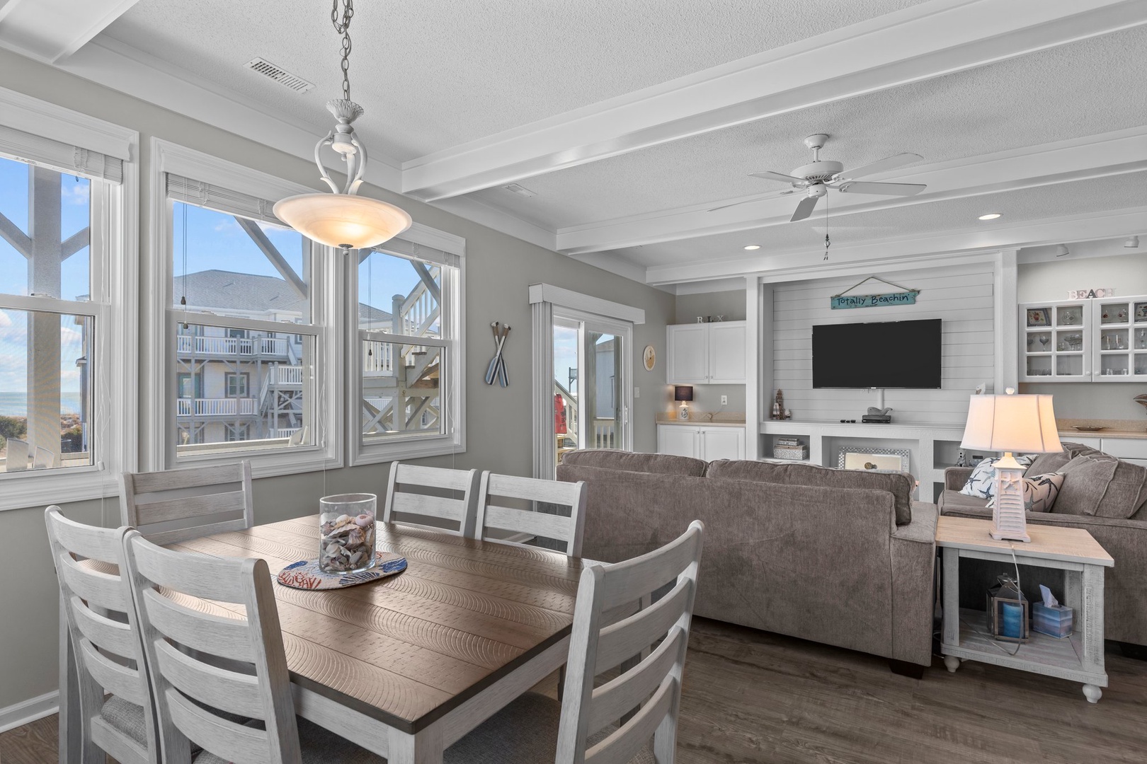 Relax in your open-concept living space where coastal charm meets comfort, featuring soaring ceilings and windows that frame ocean views.