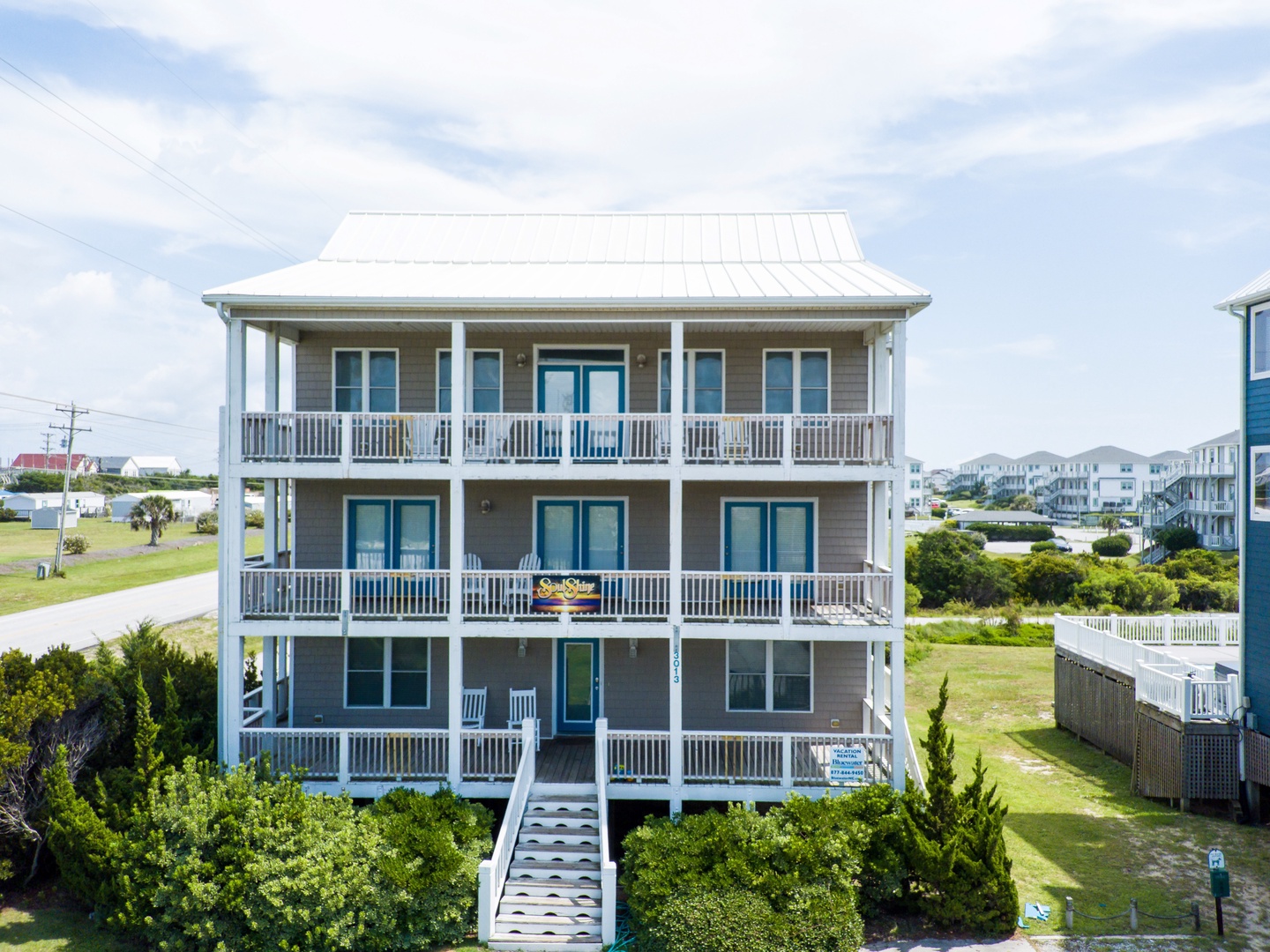 A charming three-story coastal rental with spacious balconies on every level, nestled in a peaceful neighborhood.