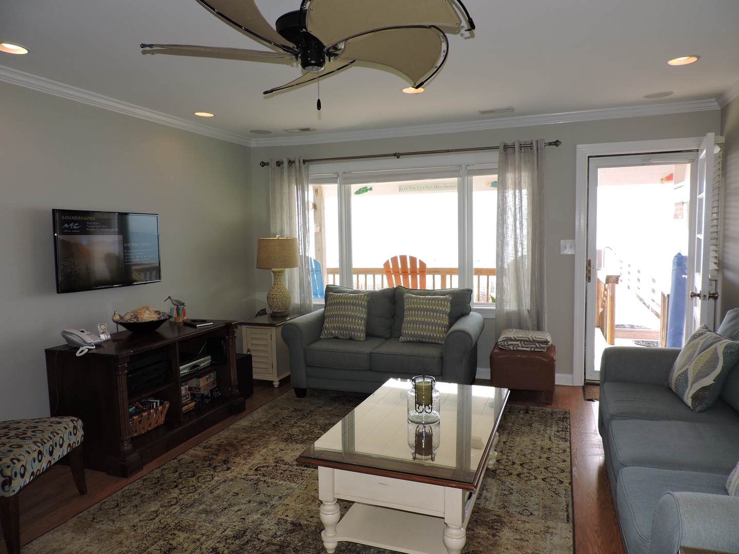 Relax in your bright living room with comfortable seating, flat-screen TV, and glass coffee table, plus direct balcony access for fresh air.