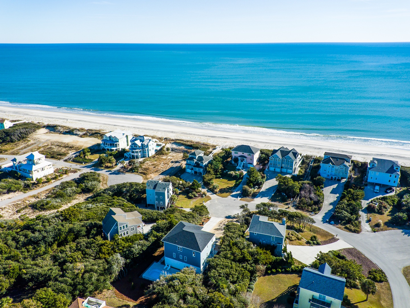 Pristine beachfront community showcasing coastal vacation homes nestled among natural dunes with direct ocean access and pristine sandy shores.