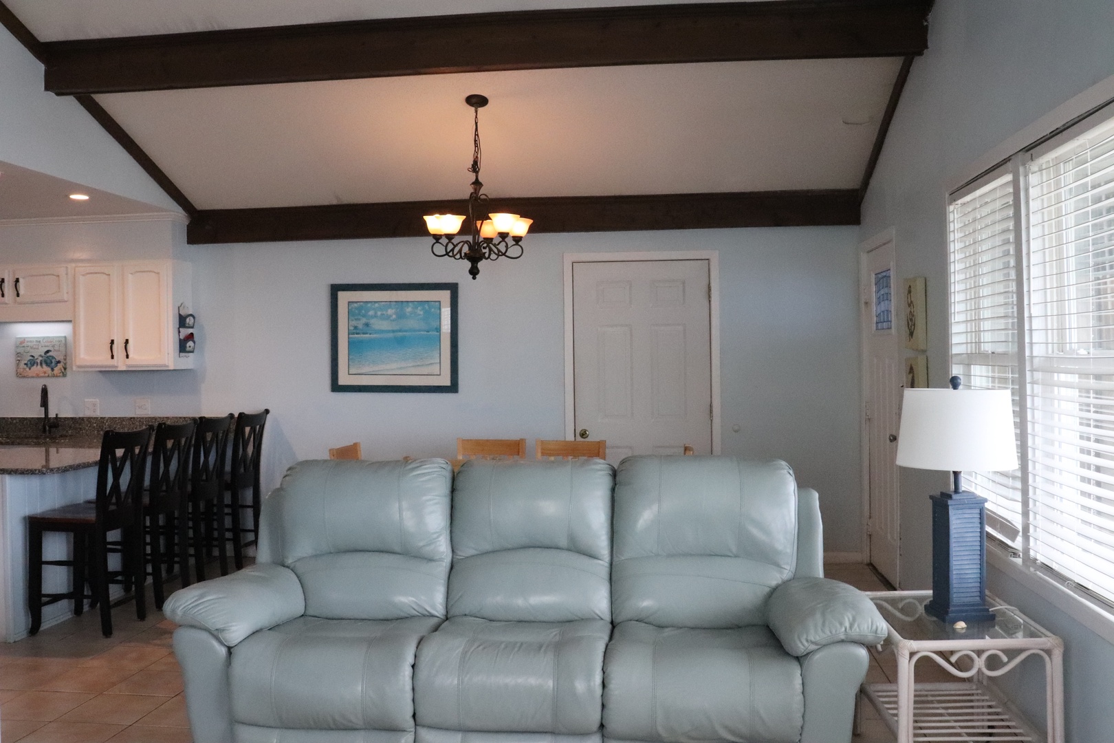 Sink into your comfortable living space, where exposed beams add rustic charm and coastal artwork invites you to unwind. Plenty of natural light and easy access to your dining area make this your perfect home base.