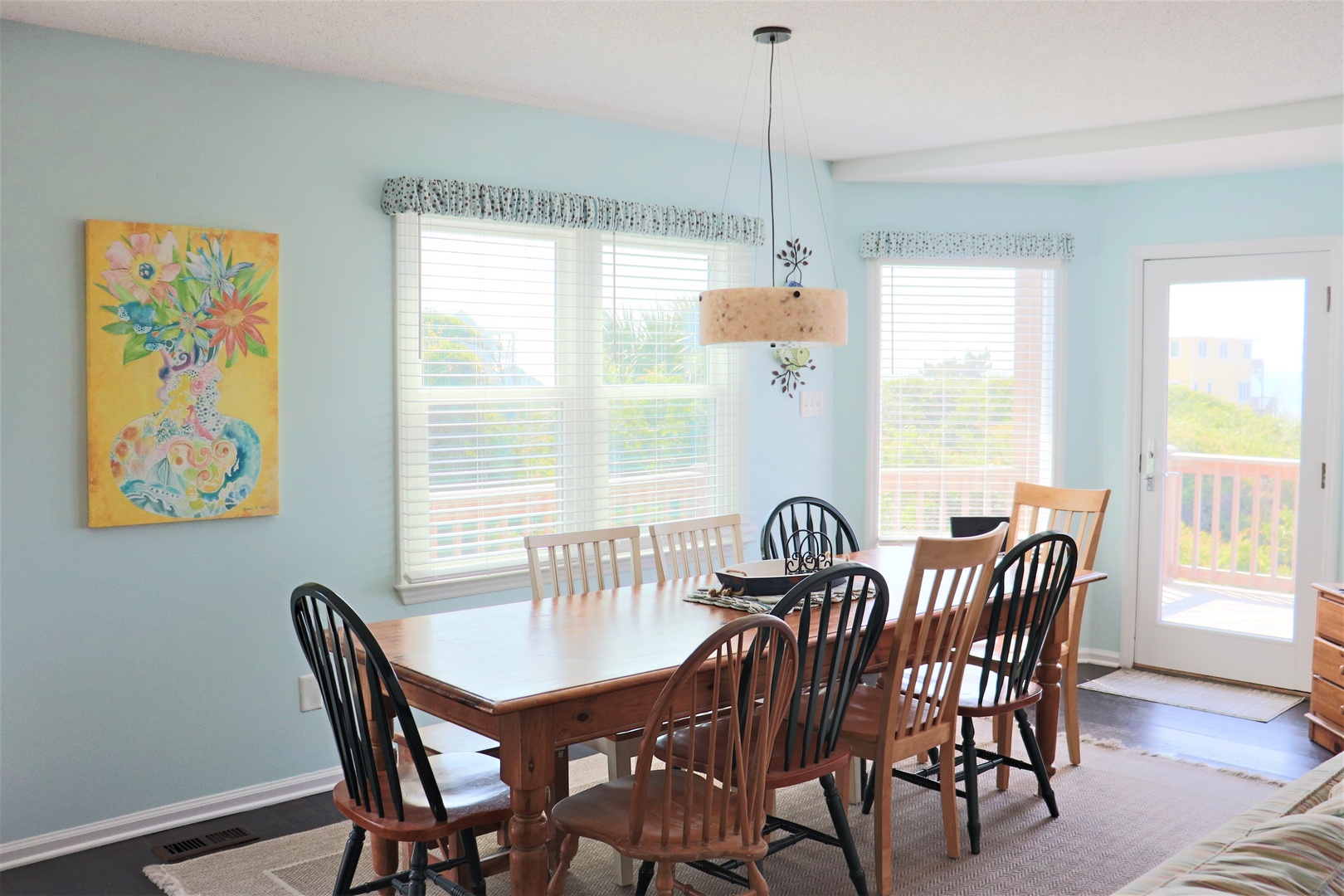 Gather around this warm dining table where memorable meals await, bathed in natural light from cheerful windows.