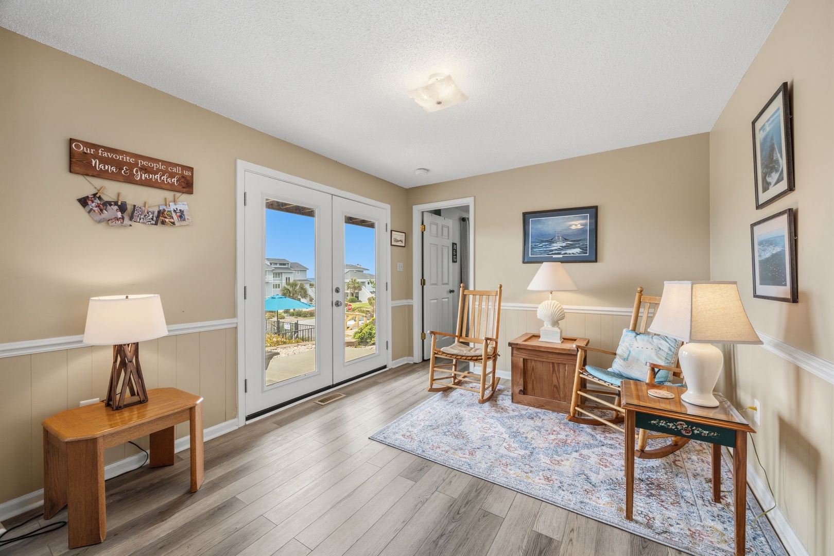 Relax in your cozy living space with nautical charm, featuring comfortable seating and French doors opening to beautiful pool views.