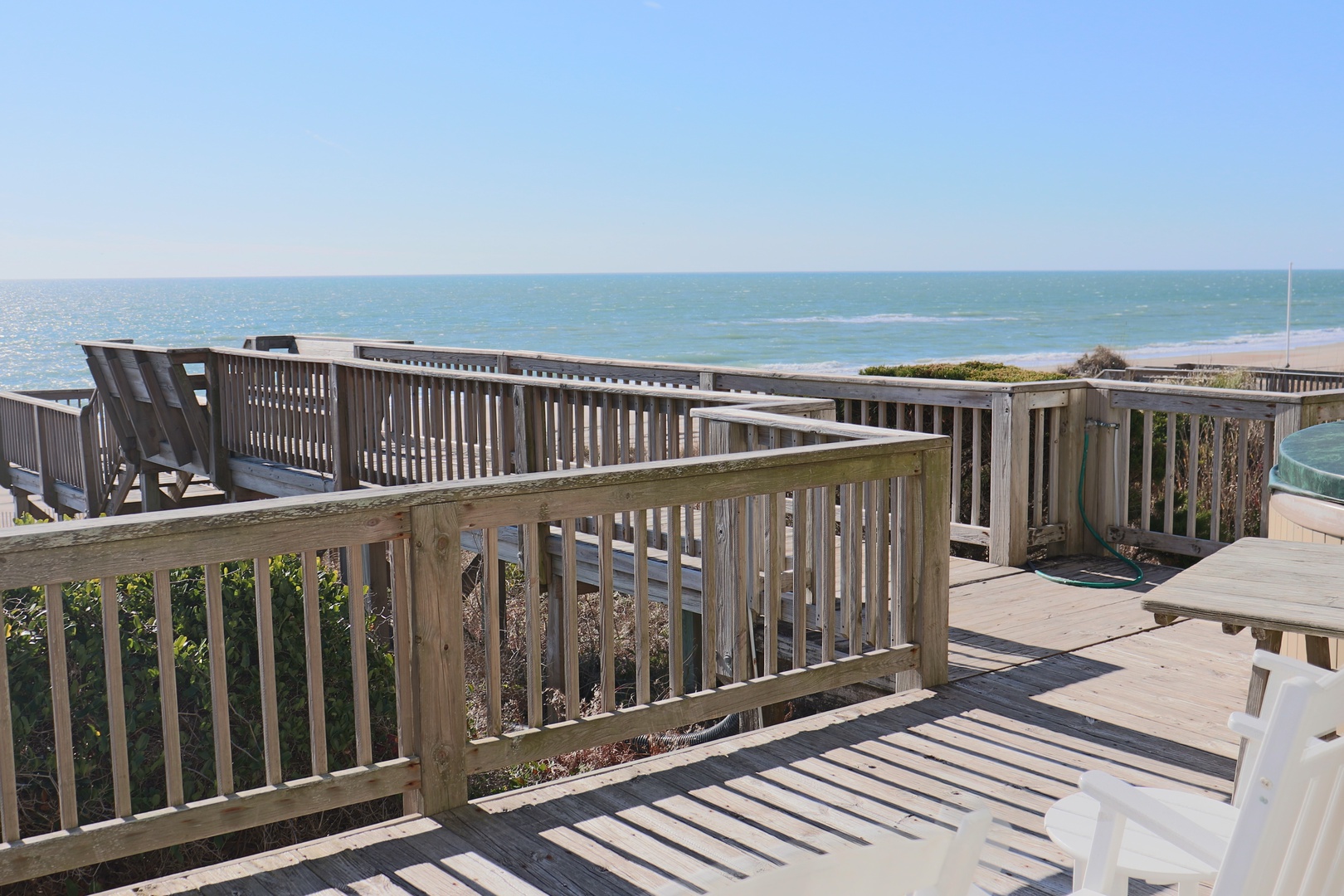 Expansive wooden deck overlooking pristine coastline with clear blue skies and ocean views.