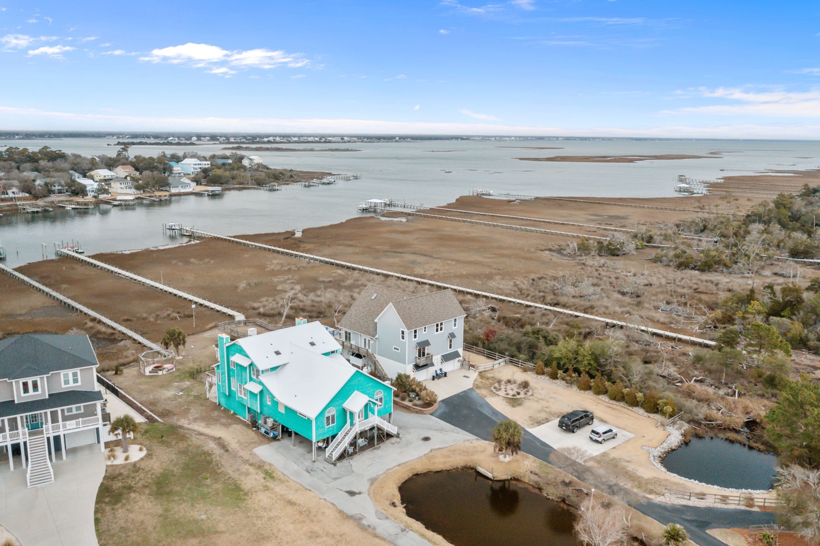 Aerial view of waterfront vacation homes nestled along pristine coastal marshlands with private docks and scenic water access.
