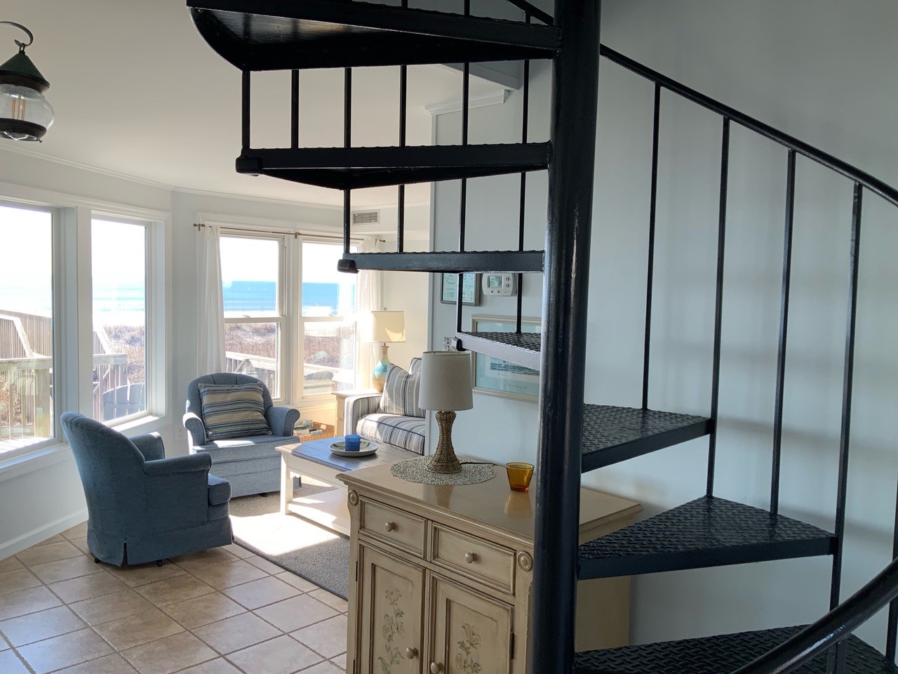 Relax in your bright living space with stunning ocean views streaming through windows. The spiral staircase adds character to this coastal retreat.
