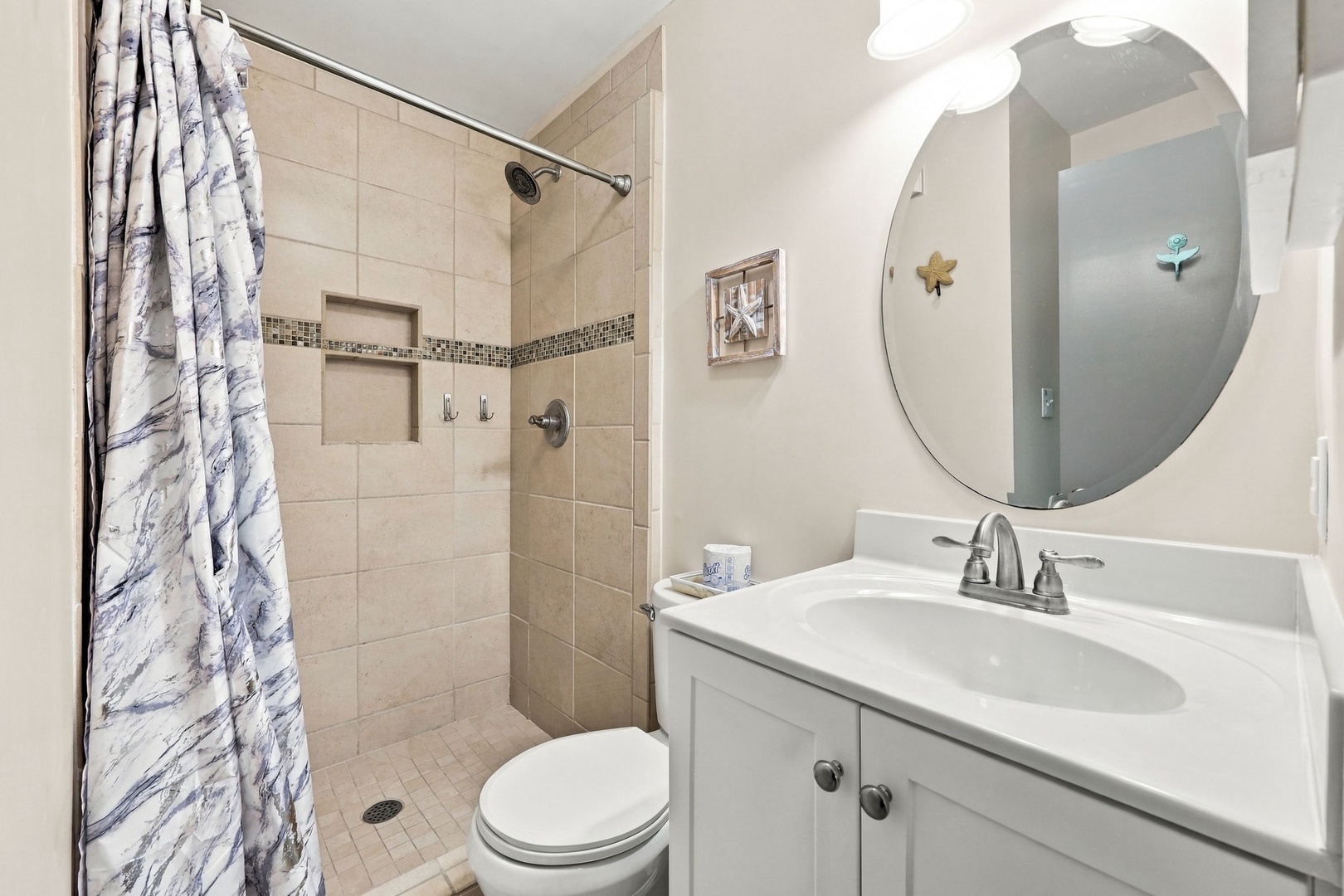 Step into your private bathroom with a spacious walk-in shower, modern fixtures, and thoughtful details like built-in shelving and a charming round mirror to brighten your morning routine.