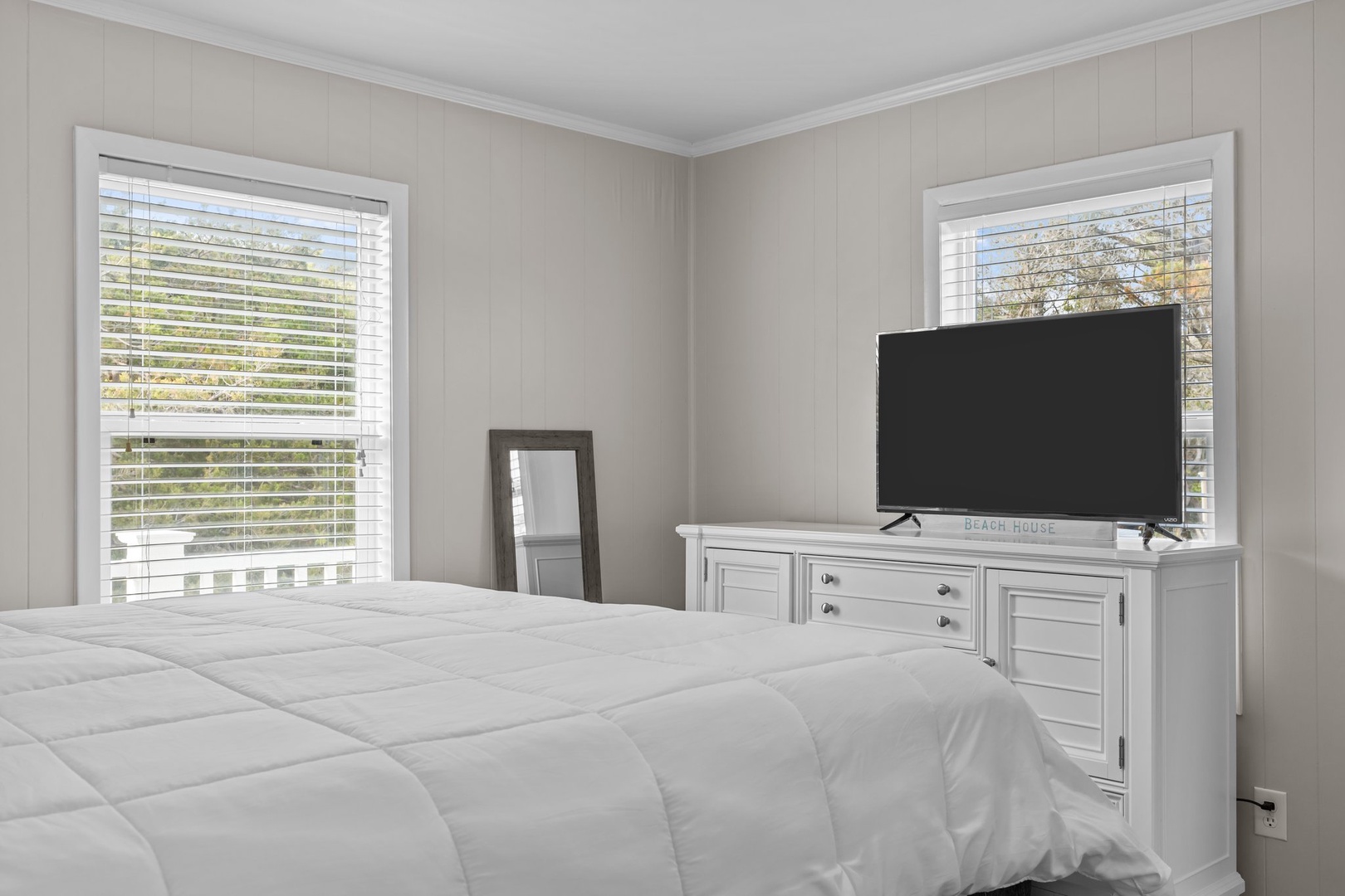 Relax in your serene bedroom with crisp white linens and modern TV entertainment, perfectly positioned for your comfort.