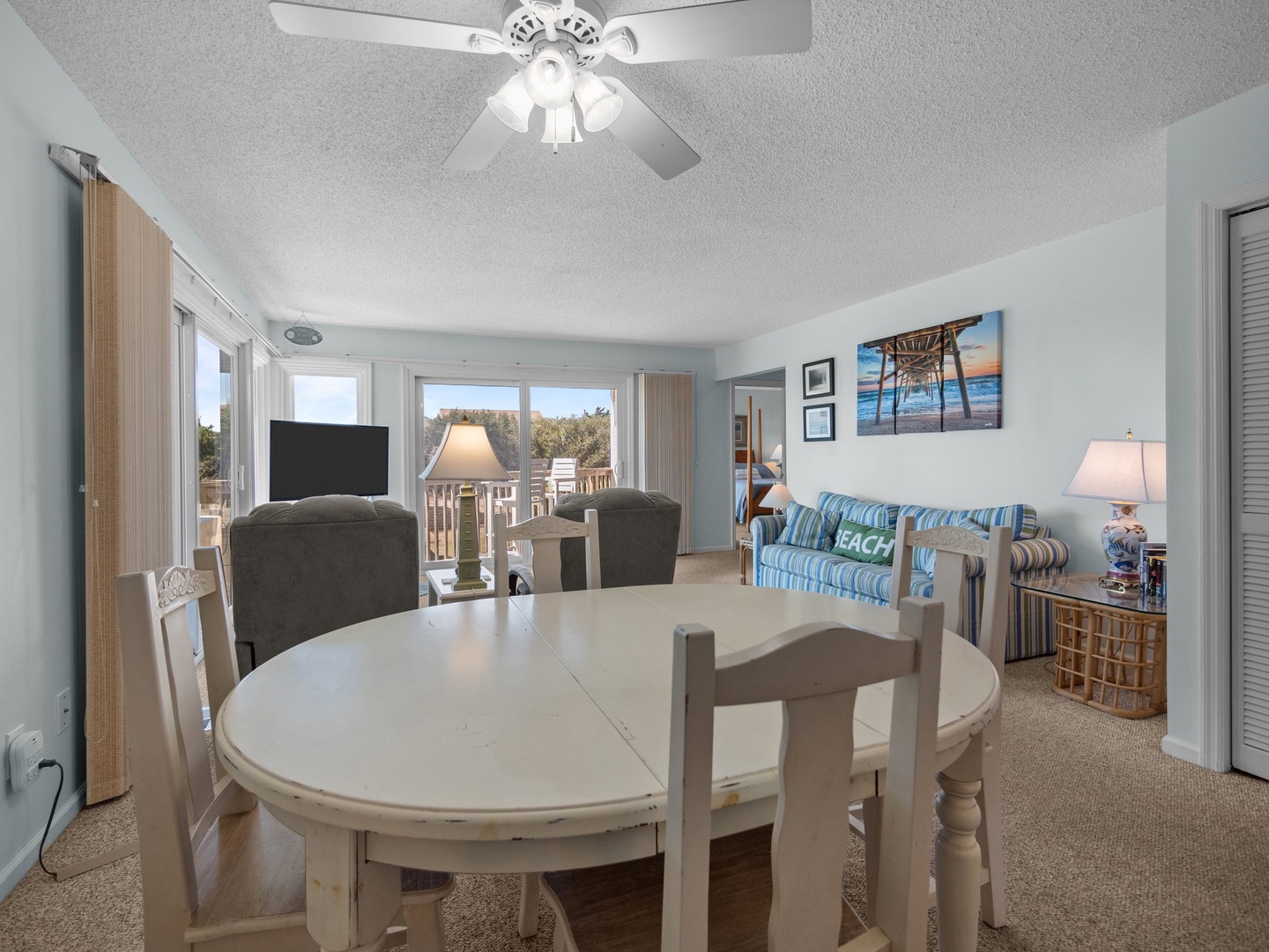 Your coastal-themed dining room flows seamlessly into the living area, where beach artwork and comfortable furnishings create the perfect retreat.