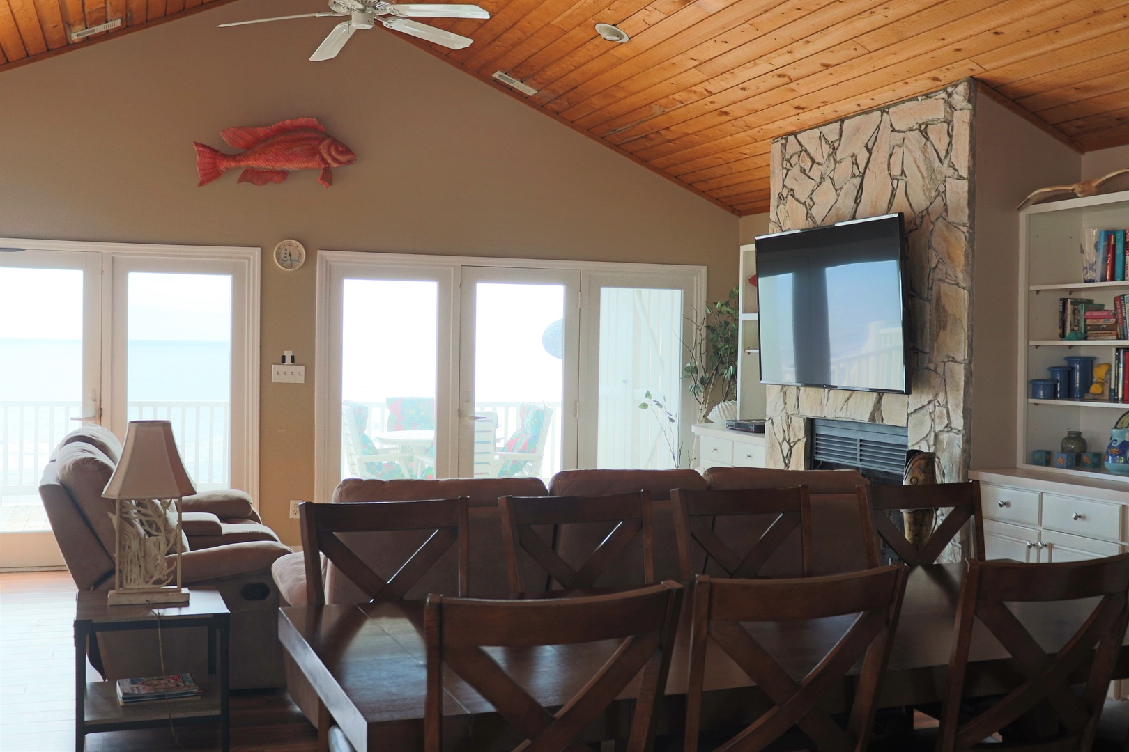 Unwind in this cozy living space with warm wood ceilings, comfortable seating, and entertainment center for your perfect lakeside retreat.