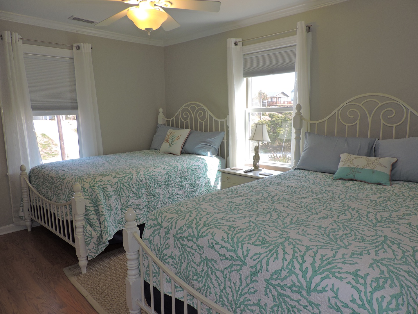 Two comfortable beds in soft coral patterns create your perfect coastal retreat with natural light.