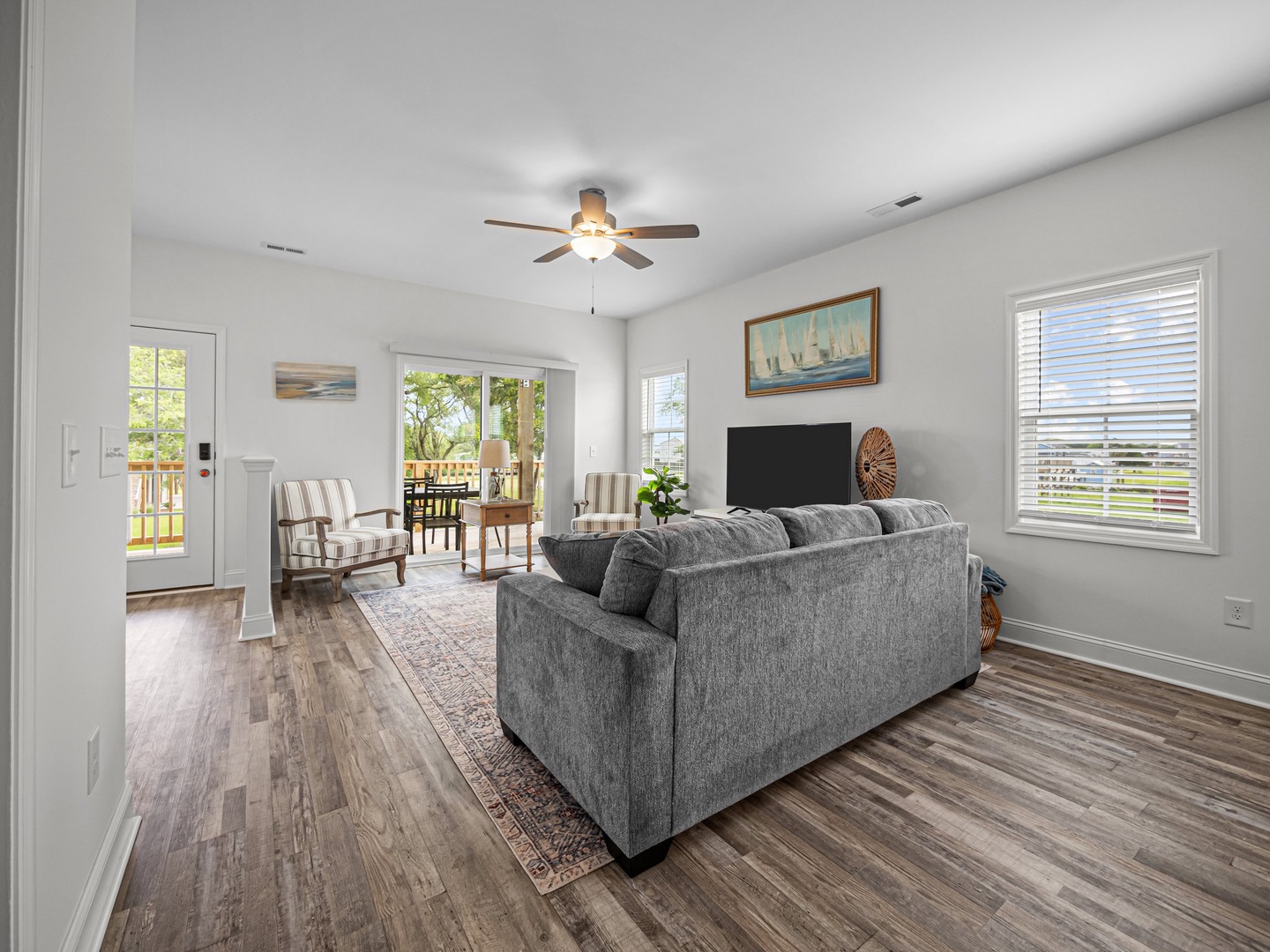 Relax in this bright, airy living room where coastal charm meets comfort—plush seating and warm wood floors create your perfect retreat.