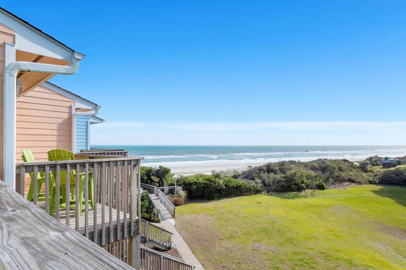 Oceanfront property featuring expansive sea views, coastal vegetation, and direct beach access with colorful beach houses nearby.