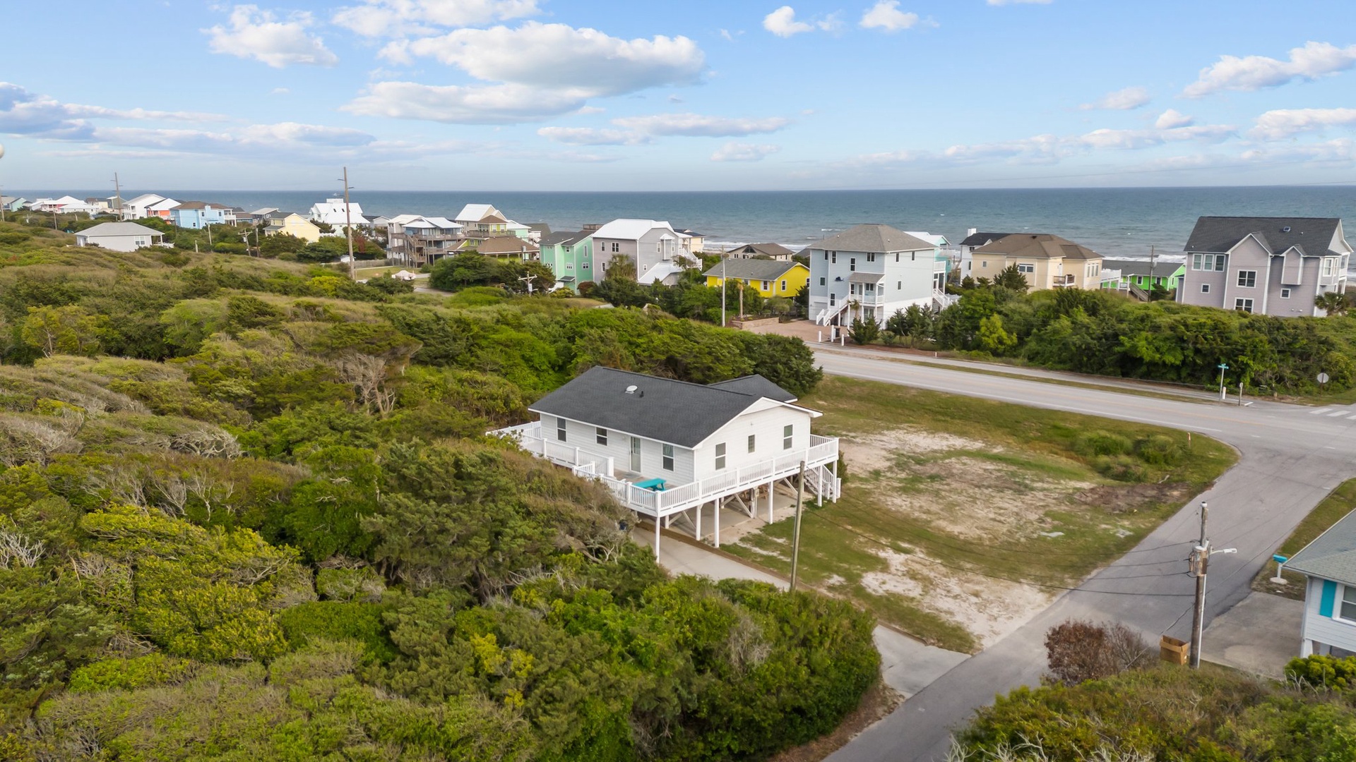 Elevated beachfront property nestled among coastal dunes, with ocean views and nearby beach house community.