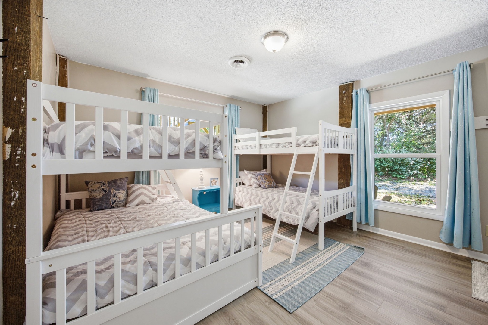 Your kids will love this bright bunk room with two sets of beds, soft natural light, and cheerful blue accents throughout.