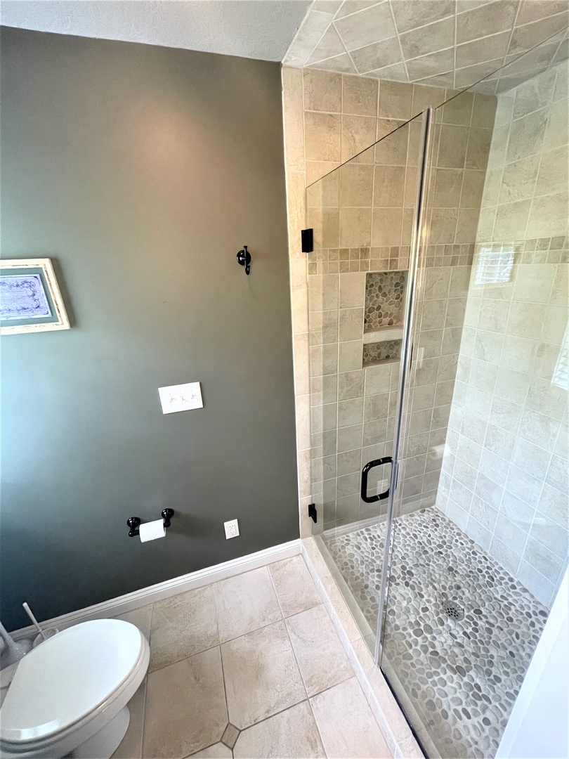 Luxurious spa-like bathroom with stone tile shower and river rock floor to rejuvenate after your day of exploring.