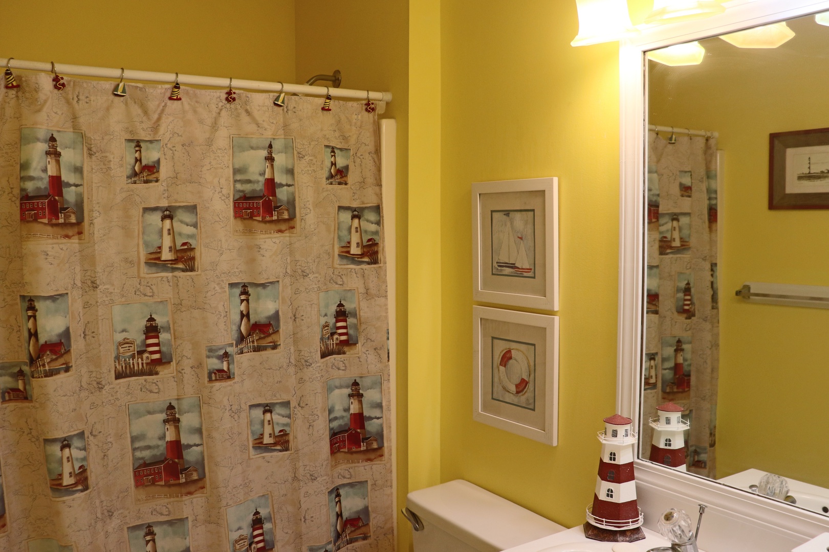 Embrace coastal charm in your private bathroom with lighthouse-themed touches and sunny yellow walls that brighten every morning routine.