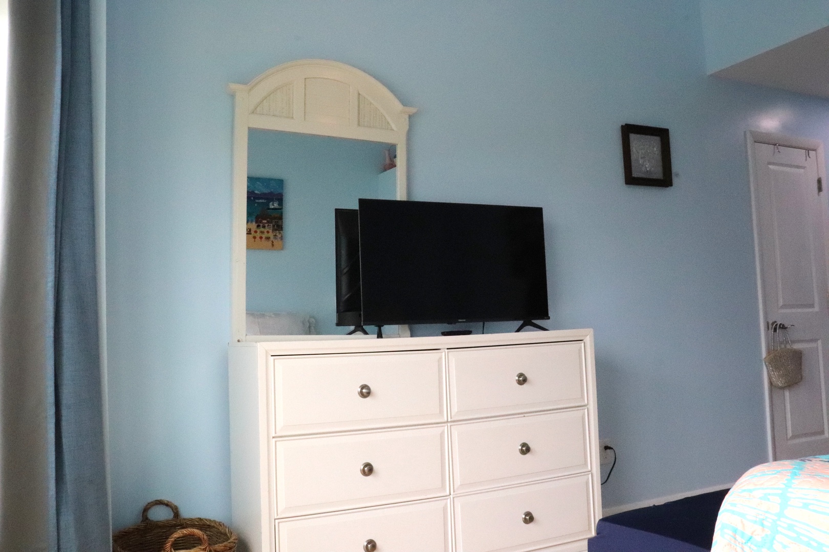 Unwind in your serene coastal-themed bedroom featuring calming blue walls, a beach-style dresser, and a flat-screen TV for your entertainment. Your peaceful retreat awaits.