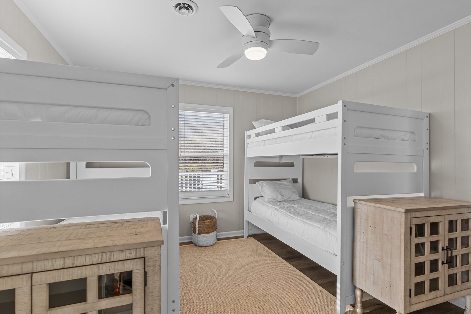 Cozy bunk room with fresh linens awaits your group adventures, featuring modern comfort and charming coastal touches.