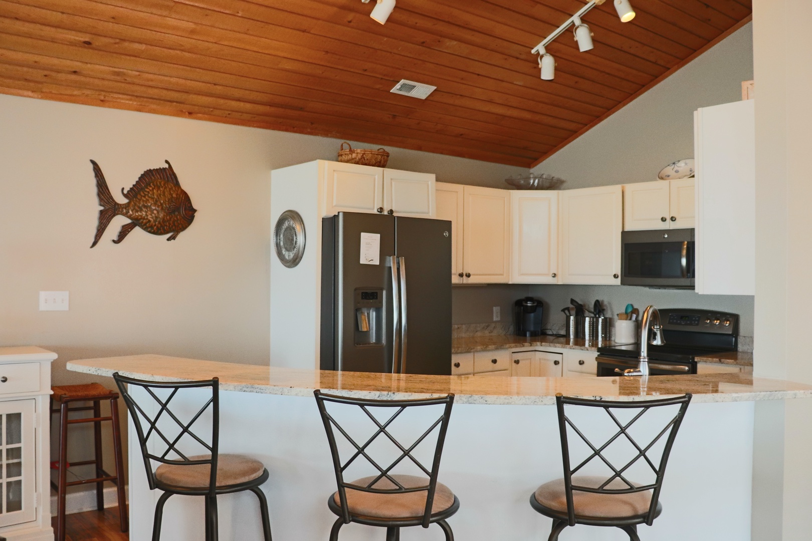 Gather around the spacious kitchen island where warm wood ceilings and granite counters create the perfect spot for morning coffee or evening conversations.