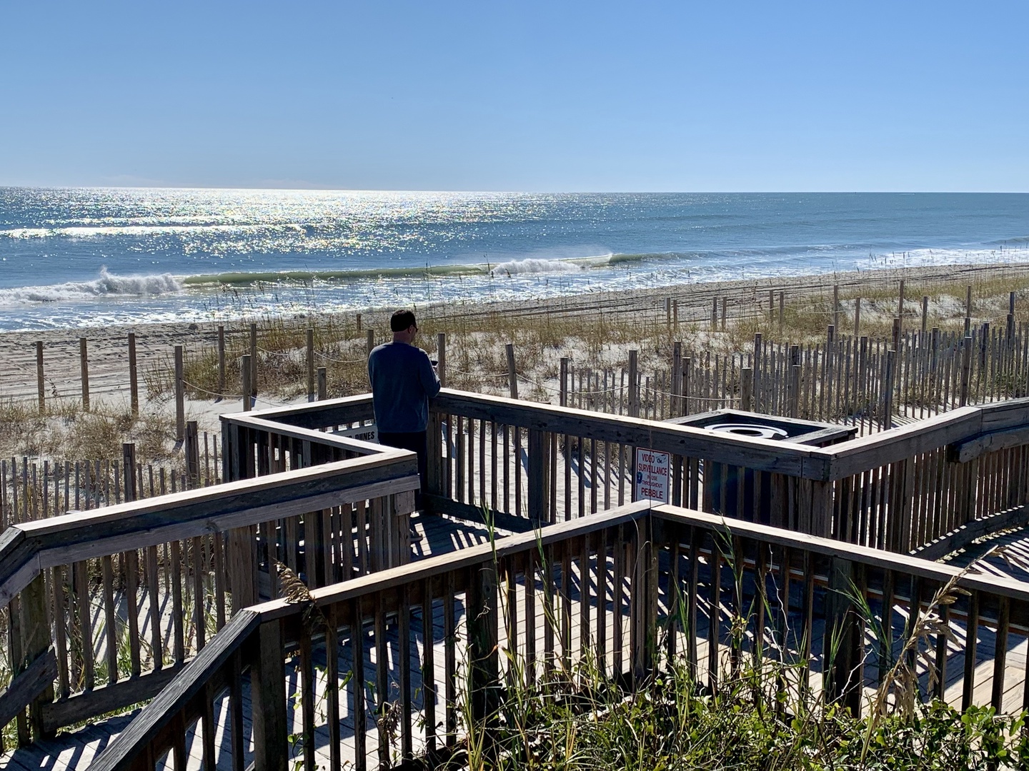 Beach access boardwalk leading to pristine shoreline with ocean waves and protected dune areas.