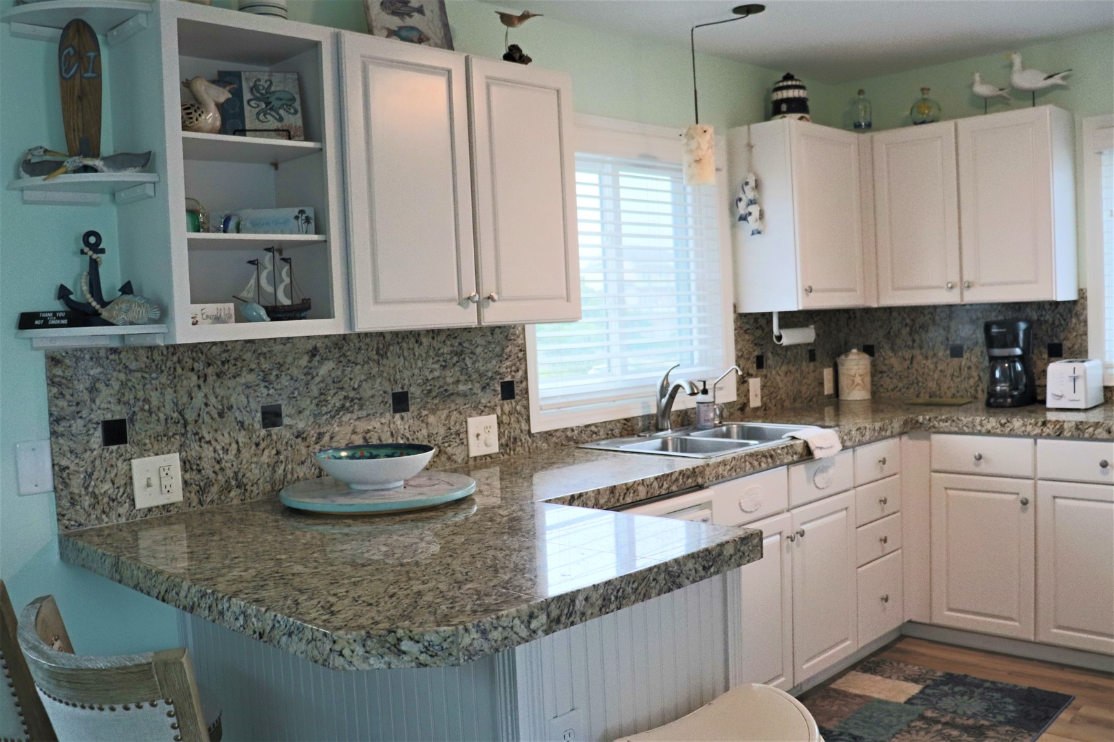 Your coastal-themed kitchen welcomes you with granite counters, white cabinets, and charming nautical touches throughout.