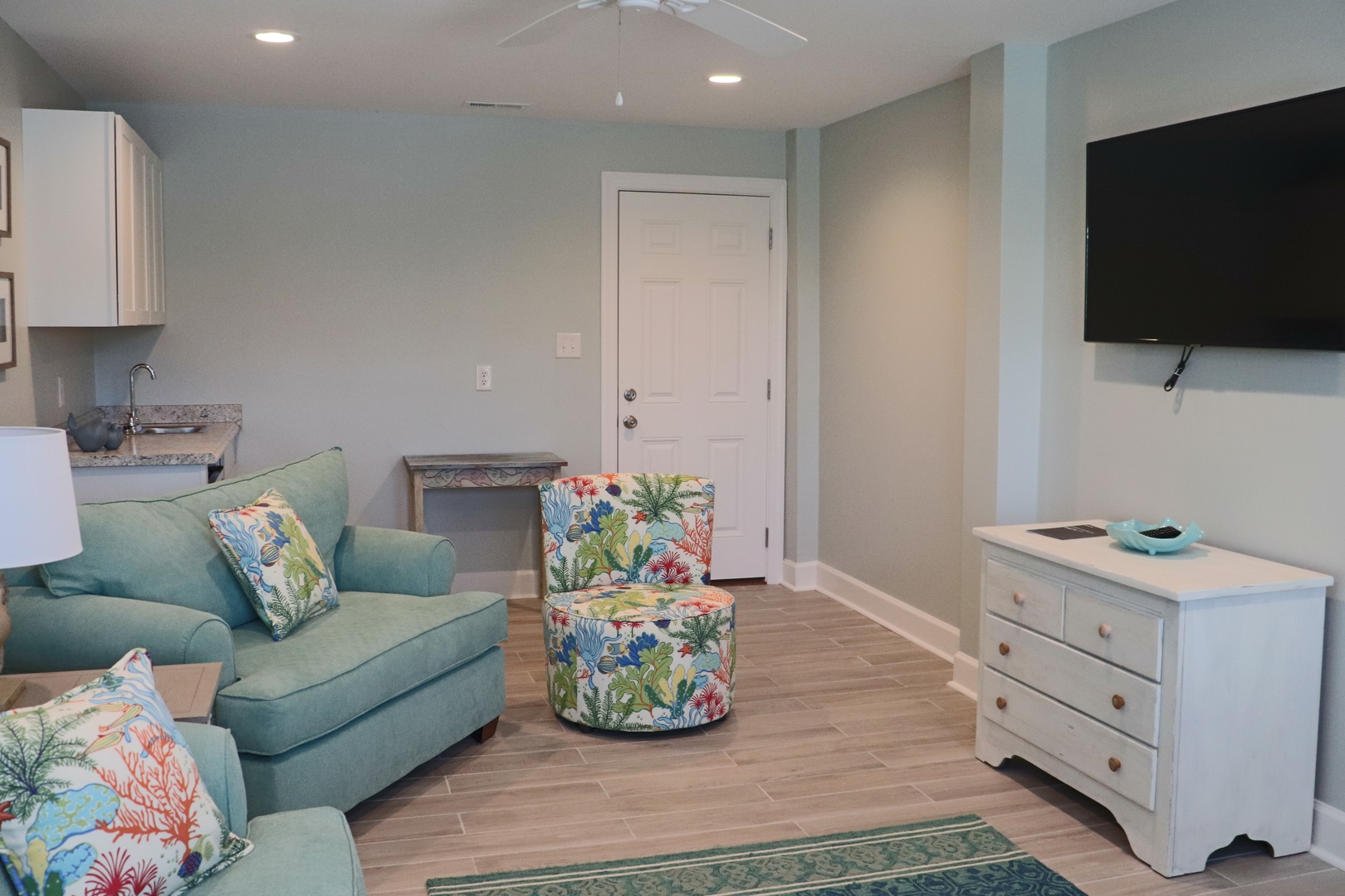 Relax in your coastal-inspired living space featuring soft aqua furnishings and tropical accents that create the perfect beach getaway atmosphere.