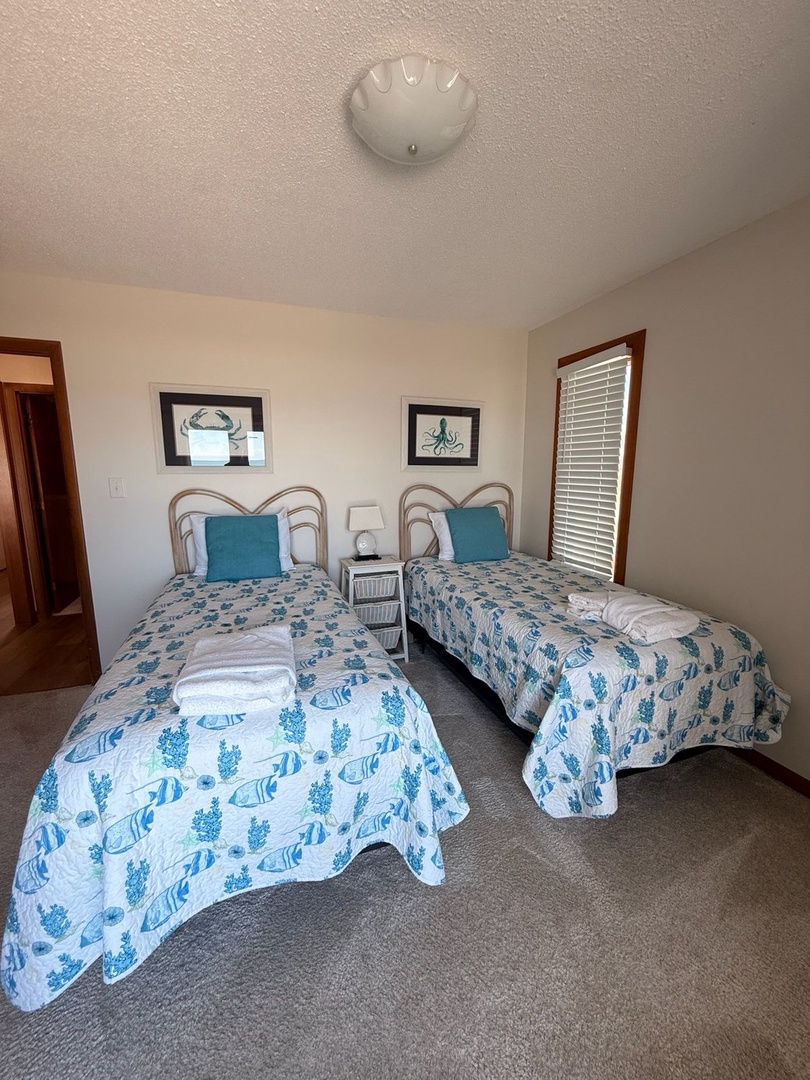 Rest easy in your coastal-inspired retreat with two comfortable twin beds dressed in ocean-themed linens. Fresh towels await, and the cheerful decor brings beachy vibes right to your room.