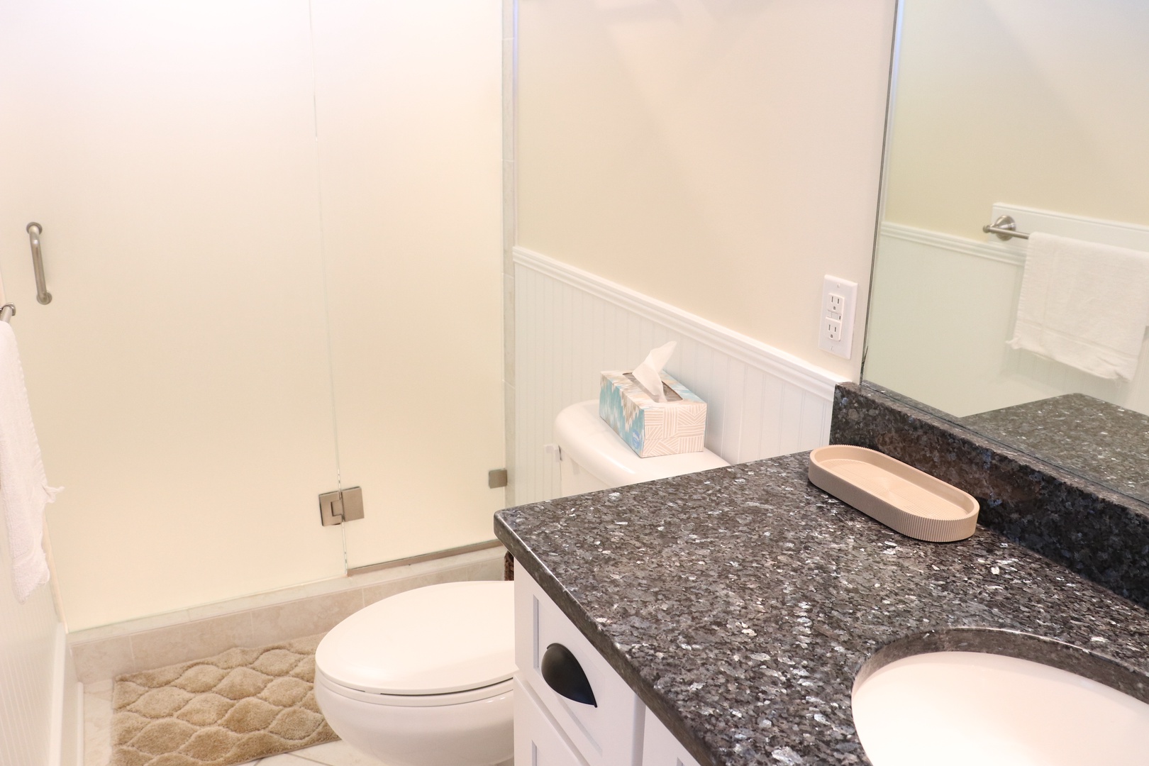 Unwind in your pristine bathroom featuring elegant granite counters, modern fixtures, and a luxurious glass-enclosed tub perfect for relaxing soaks.