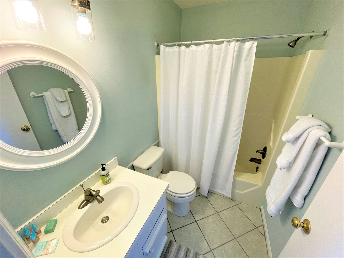 Your private bathroom features a soothing mint-green color scheme with fresh towels and a relaxing tub-shower combo for unwinding after your adventures.