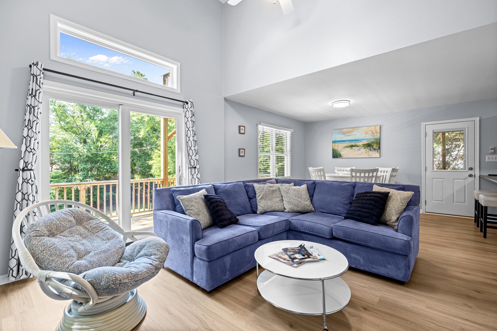 Relax on the plush blue sectional while natural light streams through large windows overlooking lush greenery from your peaceful treetop retreat.