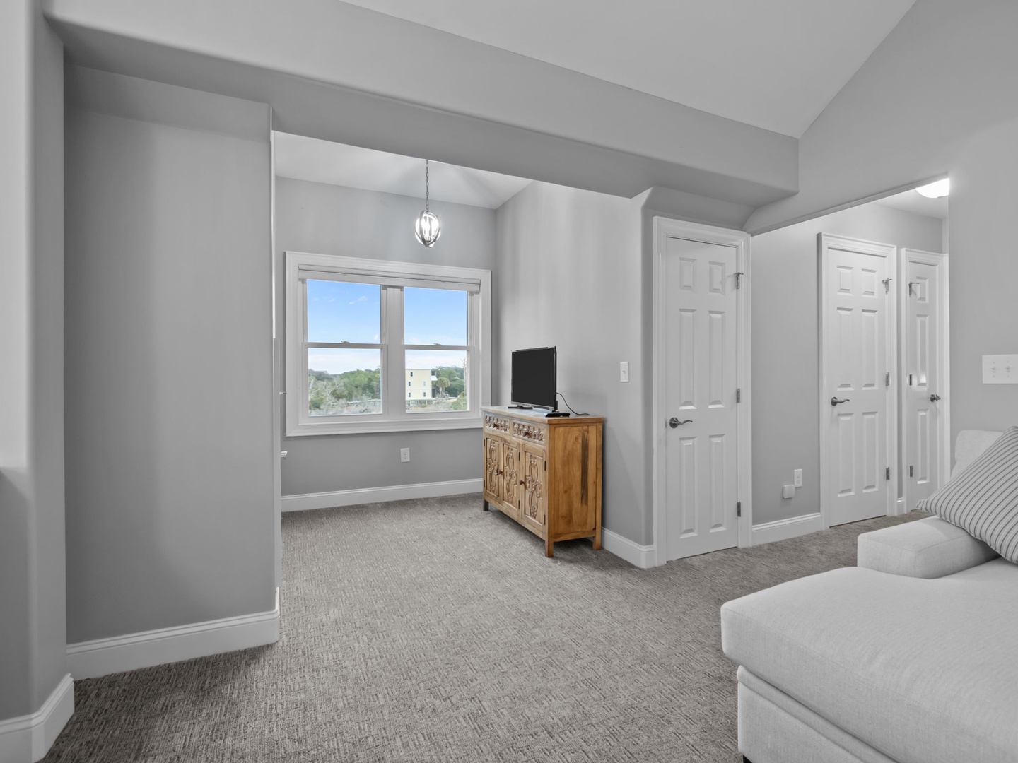 Relax in your bright living space with soft gray walls, plush seating, and a window framing peaceful neighborhood views.