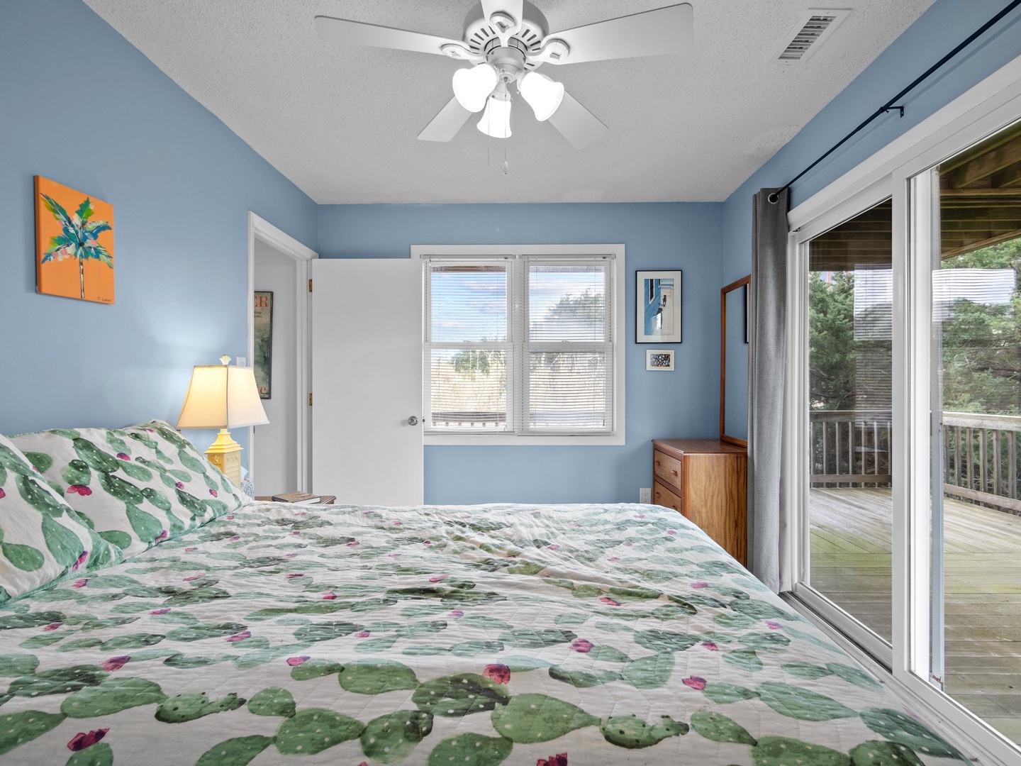 Drift off in your tropical-themed bedroom with soothing blue walls, ceiling fan breeze, and private deck access.