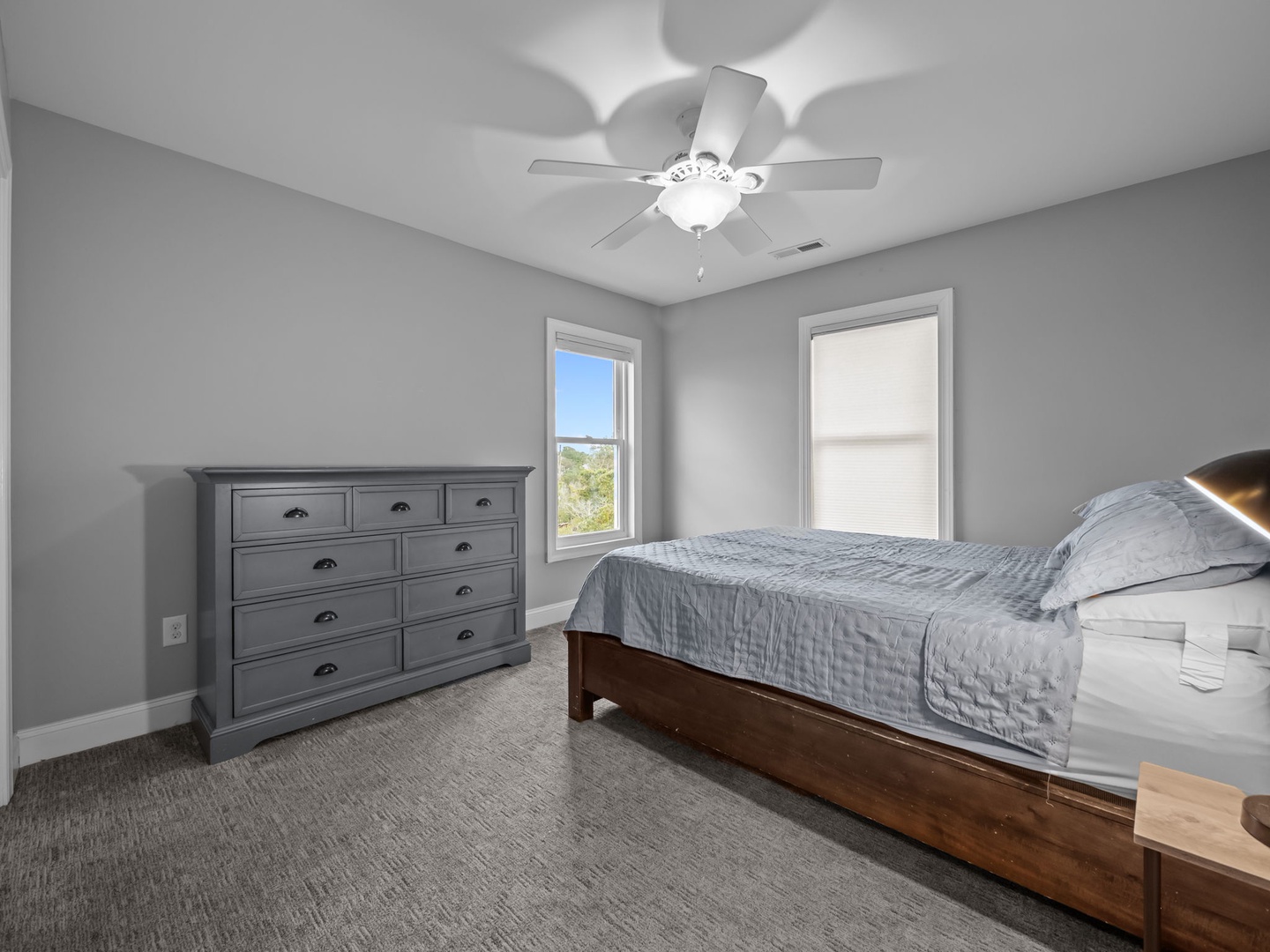 Your peaceful bedroom features plush carpeting, a ceiling fan for comfort, and natural light streaming through windows.