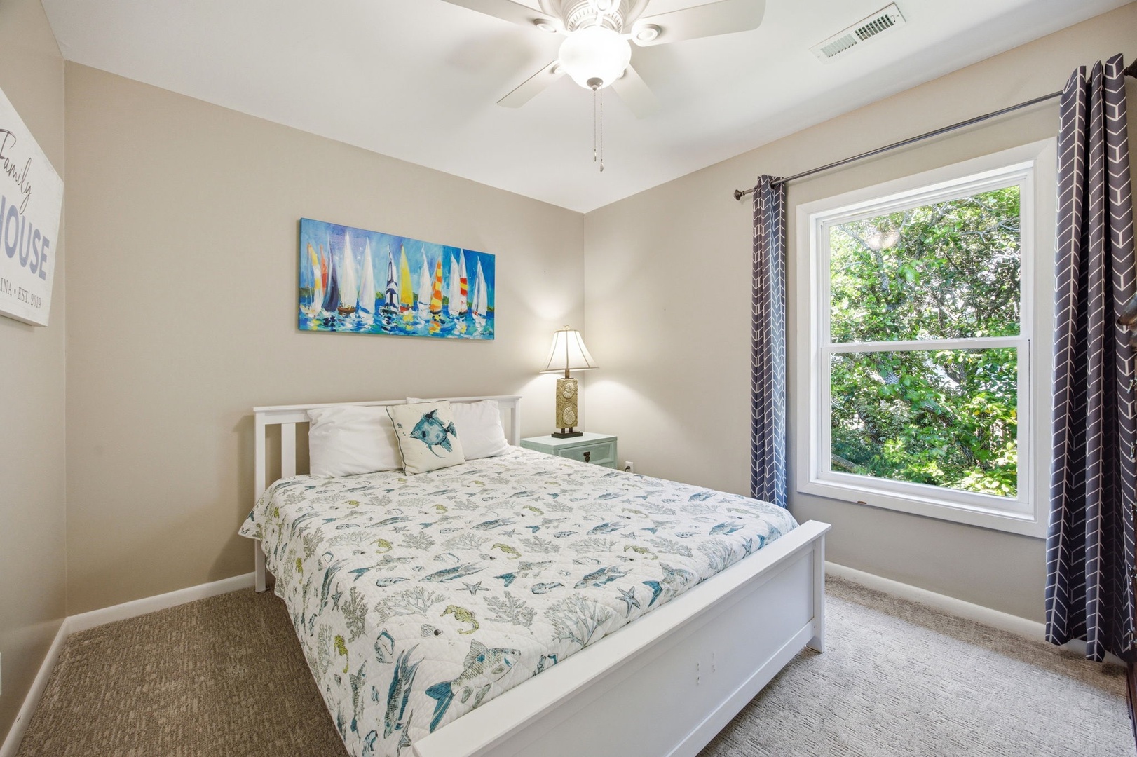 Wake up refreshed in this peaceful bedroom featuring crisp linens and calming ocean-themed artwork, with natural light streaming through your garden view window.