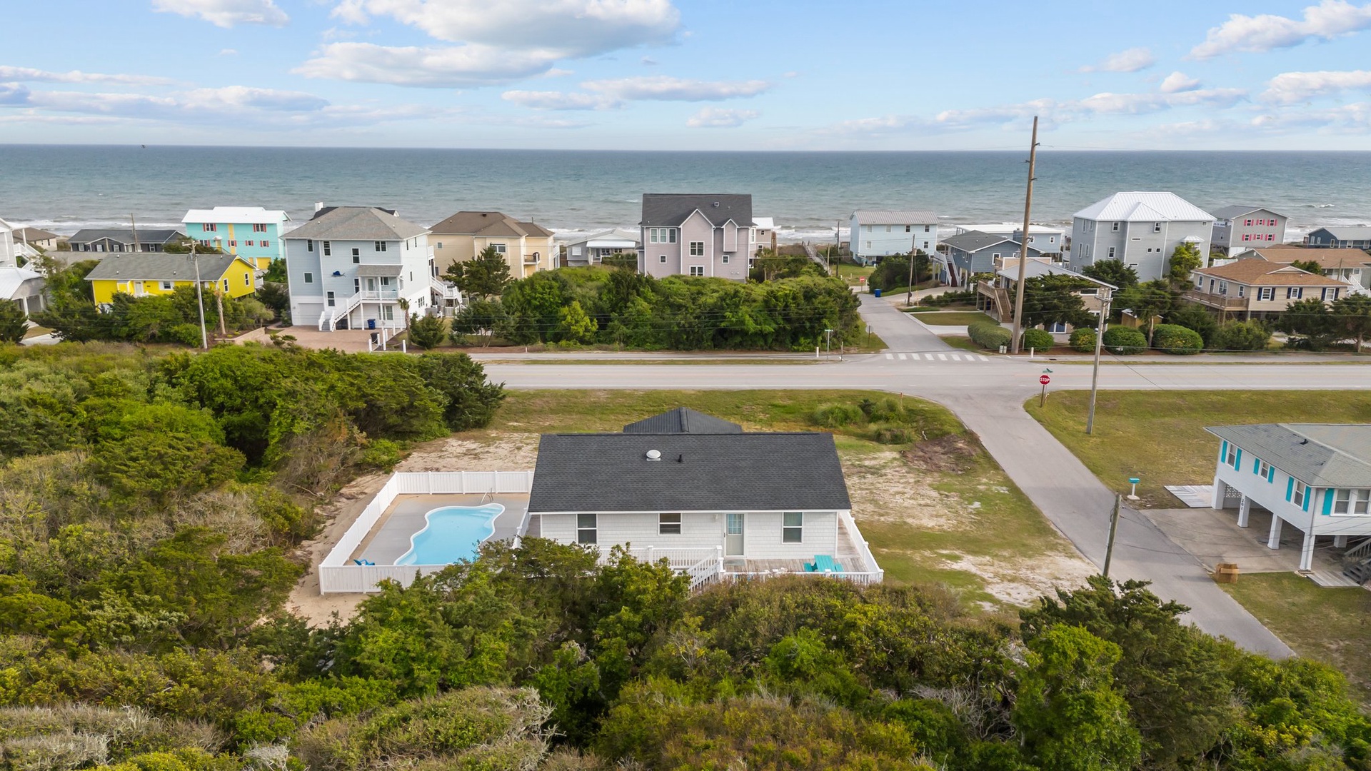 Aerial view of coastal vacation rental with private pool, nestled among beach homes just steps from the ocean.