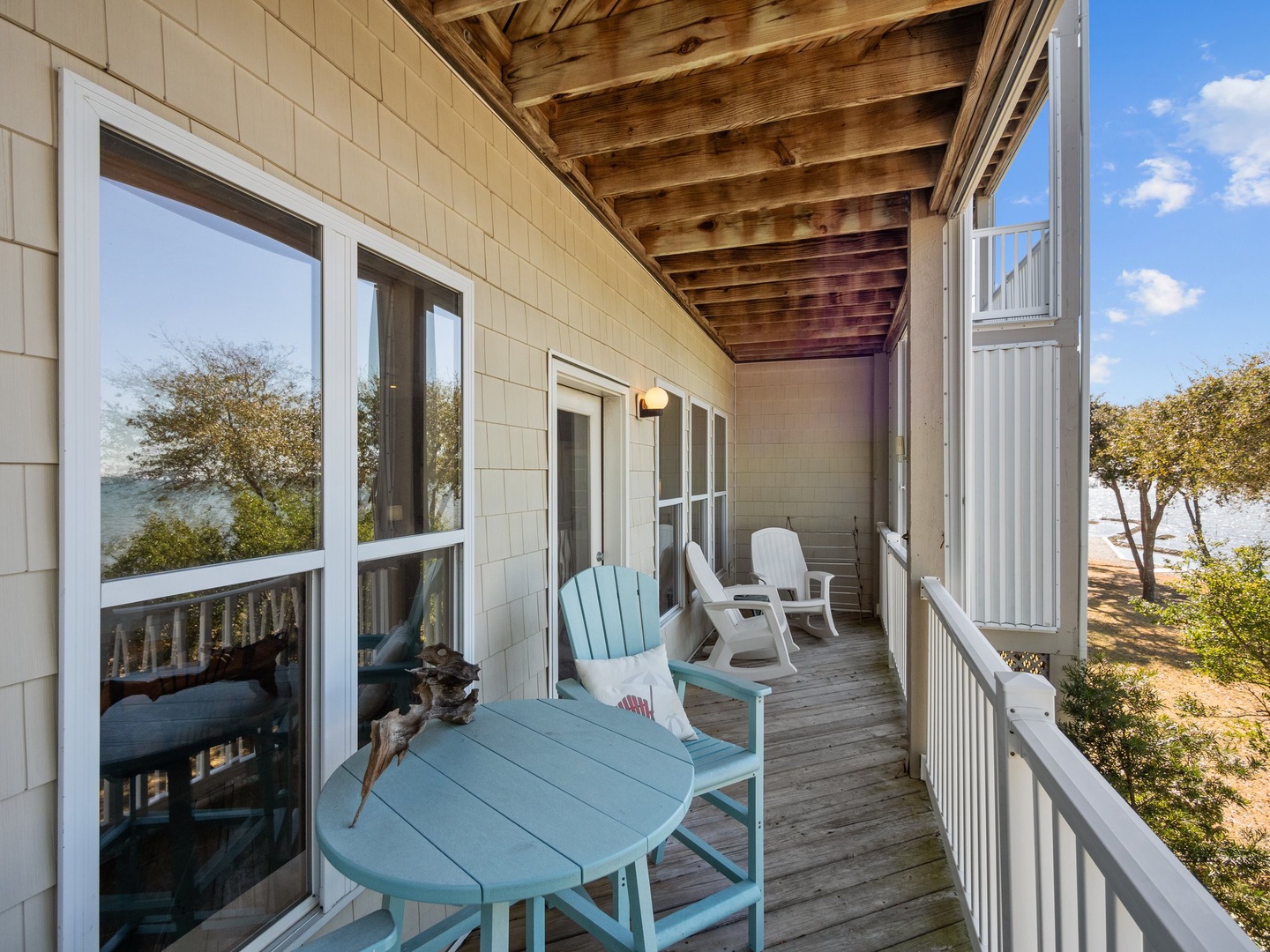 Your waterfront porch invites you to unwind with coastal-colored furniture, exposed beam ceiling, and stunning views through tall windows.