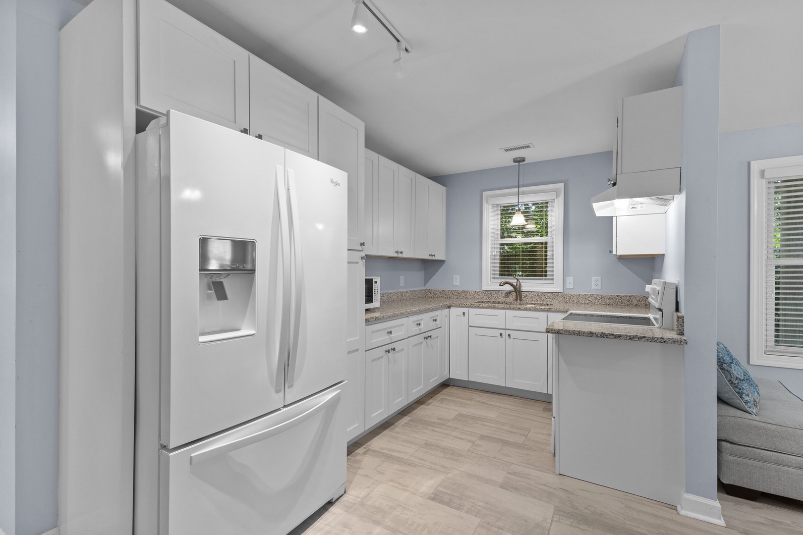 Your modern kitchen awaits with granite countertops, white appliances, and plenty of space for preparing meals.