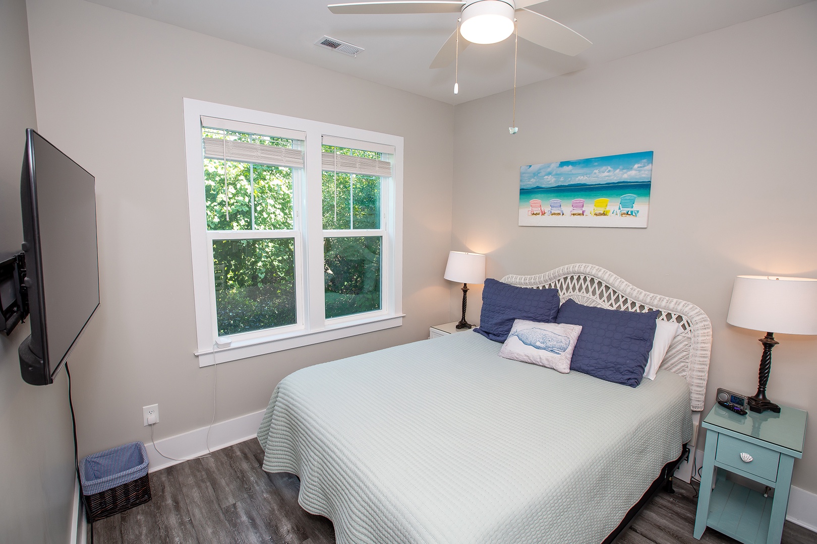 Drift off to peaceful dreams in your bright bedroom with coastal décor, garden views, and cheerful beach artwork creating a serene escape.