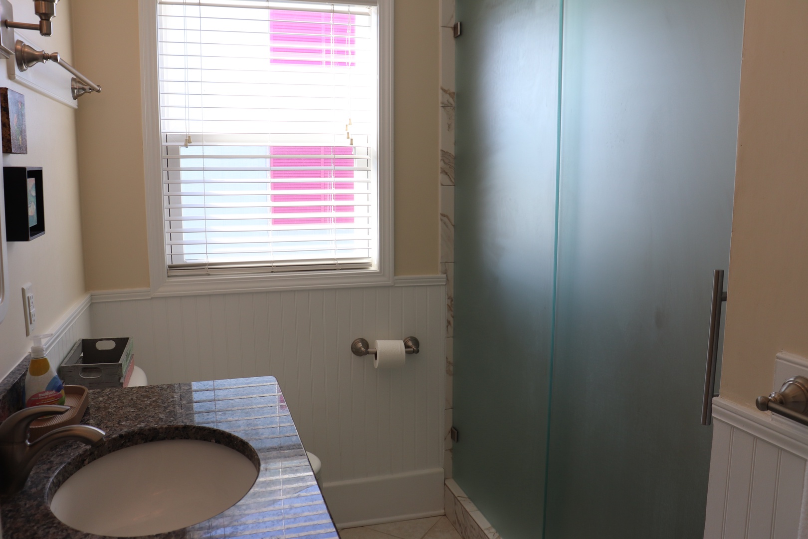 Refresh in your private bathroom with walk-in glass shower, granite vanity, and natural light streaming through frosted windows.